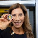 Freddie Mercury's sister, Kashmira Bulsara, holding the new Royal Mint commemorative coin. The design features Mercury mid-performance, his signature, and details like his Live Aid outfit (Photo: Royal Mint)