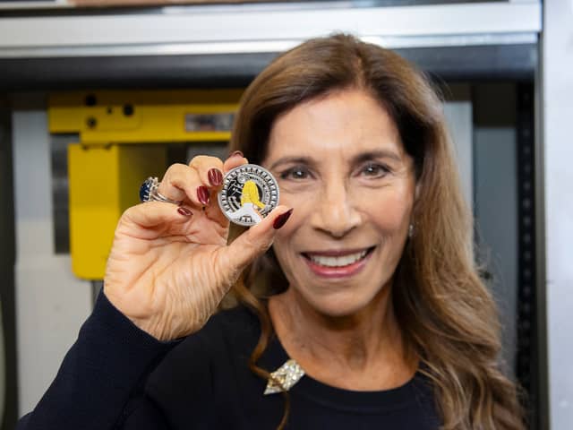 Freddie Mercury's sister, Kashmira Bulsara, holding the new Royal Mint commemorative coin. The design features Mercury mid-performance, his signature, and details like his Live Aid outfit (Photo: Royal Mint)