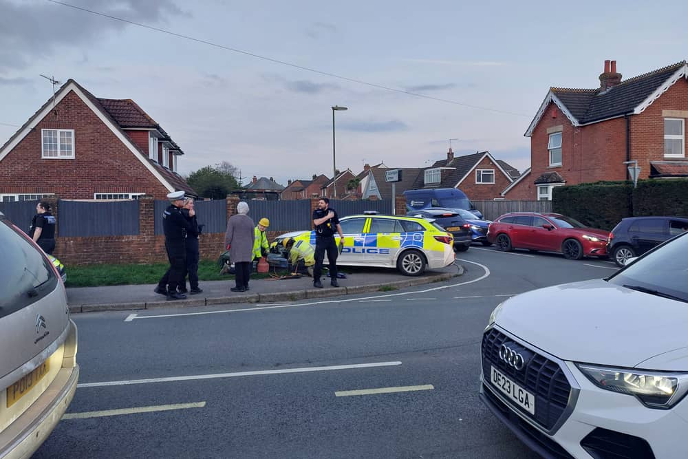 The police car was responding to an emergency when it collided with another car and left the road crashing into a green cabinet.