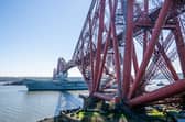 HMS Queen Elizabeth passes under the Forth Bridge heading out to sea after leaving Rosyth, The Royal Navy aircraft carrier is back on the water after months on the side-lines.