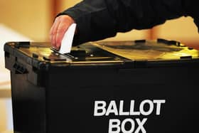 A voter places a ballot paper in the ballot box at the polling station