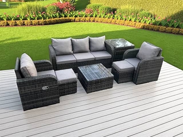 The seven-seater dark grey rattan garden furniture set includes reclining chairs, footstools and two tables.