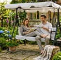 The three-seater swing chair includes an adjustable canopy and cushioned seating for relaxed garden afternoons