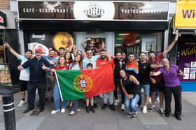 Portugal supporters outside Cafe Prazeres during Portugal's opening game of the World Cup on Wednesday, June 17. Janete Bichinho, Pedro Bichinho and Daniel De Freitas are holding the Portuguese flag.
