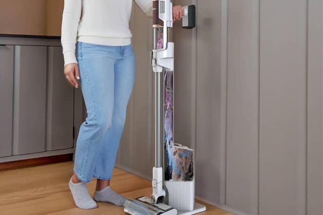 Shark’s Clean & Empty cordless vacuum returns to its charging dock after use, where collected dirt is transferred into a larger sealed base