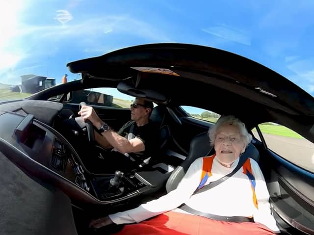 Patricia Elliot being driven in an Aston Martin at Thruxton Race Circuit near Andover
