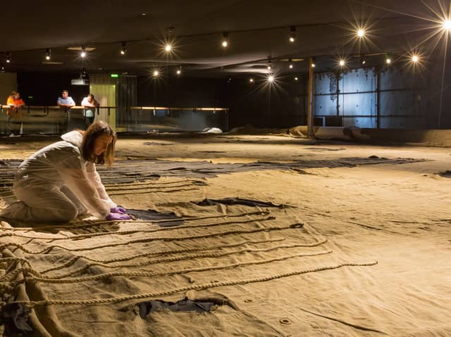 Senior conservator Diana McCormack making final checks on the Trafalgar Sail before its limited display at Portsmouth Historic Dockyard