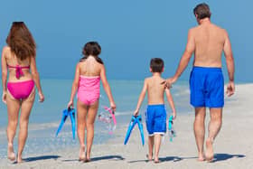 A happy family of mother, father and child, a daughter, walking in swimming costumes on a sunny beach