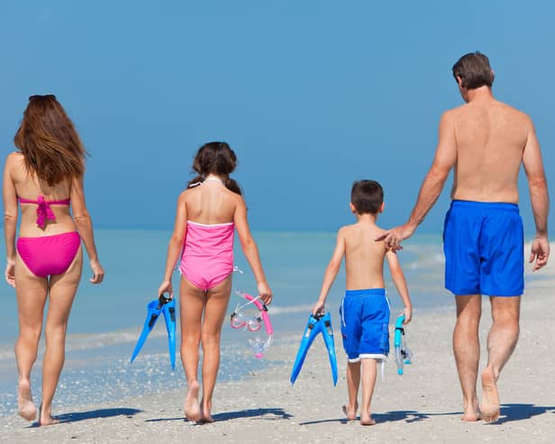 A happy family of mother, father and child, a daughter, walking in swimming costumes on a sunny beach