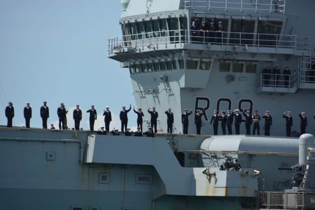 The crew of the HMS Prince of Wales wave as it sets sails from Portsmouth Naval Base.