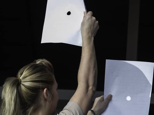 A woman uses two sheets of paper as the Sun is obscured by the Moon during a partial solar eclipse at Skegness seafront in Lincolnshire, north England on 20 March 2015.