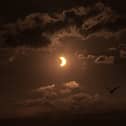 Birds fly past a partial solar eclipse, seen over Liverpool Bay from Crosby Beach on 12 August 2026 in Liverpool, United Kingdom.