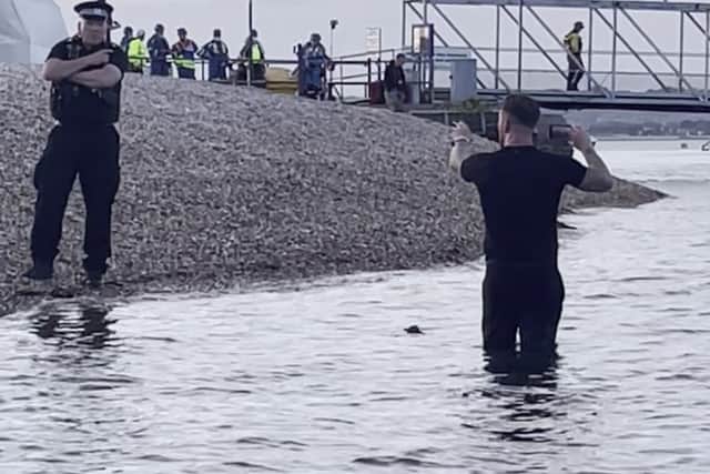 Daniel Thomas, known as Danny Tommo, standing in the water livestreaming the operation to rescue around 120 migrants who were brought into the harbour at Portsmouth.