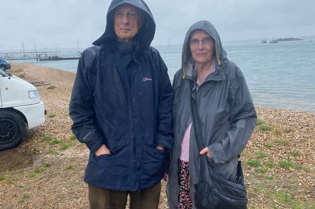 Ron and Liz Thomas at Eastney Marina with D-Day Mulberry Harbour constructions in background near pontoon where migrants were brought ashore