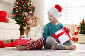 Happy children with Christmas gifts on floor at home