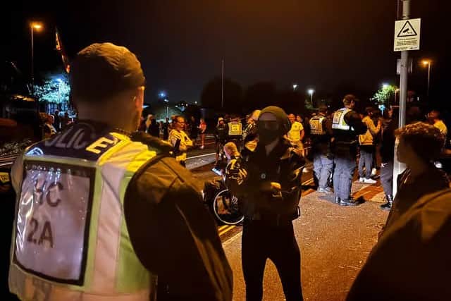 Masked protestor confronting police at Gosport migrant protest.