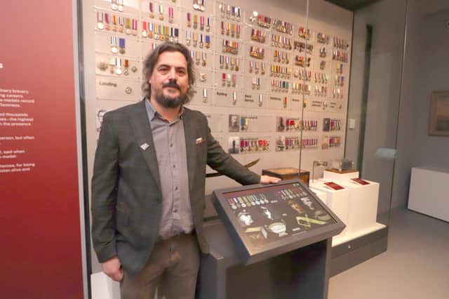 James Daly, principal curator (modern and contemporary) at the National Museum of the Royal Navy (NMRN), in front of the medal display at the new Royal Marines Museum.