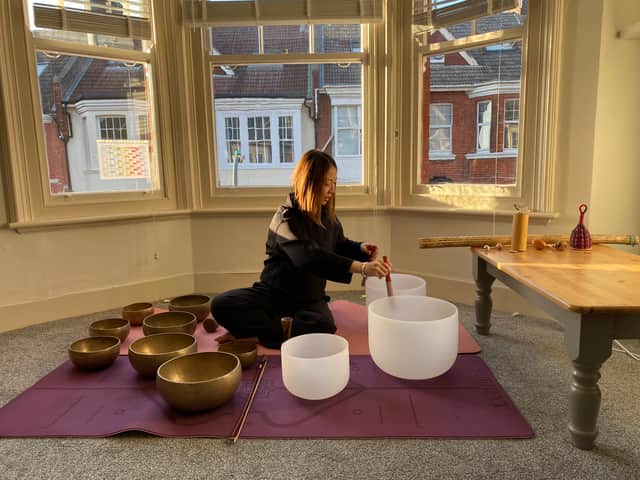 Selina Chung delivering a sound therapy session using Himalayan and crystal singing bowls in a calm, natural setting.