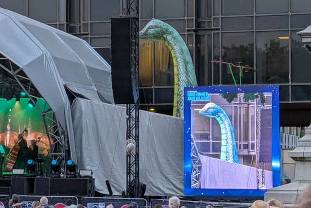 A dinosaur watches Jurassic Park by BSO: Williams and Zimmer outdoor concert