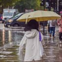 Pedestrians walk with umbrellas during heavy rain.