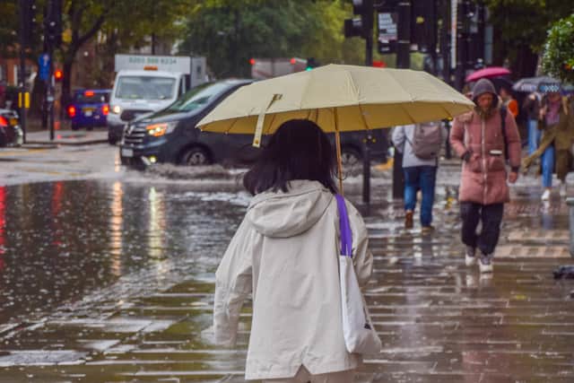 Pedestrians walk with umbrellas during heavy rain.