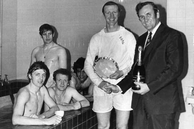 Charlton poses next to Leeds United manager Don Revie with a bottle of champagne and the Footballer of the Month trophy in April 1972. Photo by E. Milsom/Evening Standard/Getty Images.
