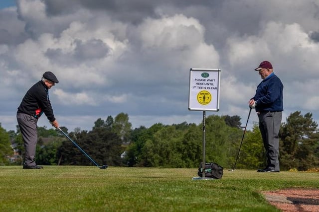 A golfer waits his turn beside the two metre distance sign