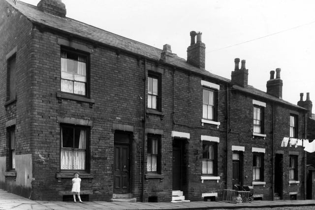 Four houses on Leith Street, seen from the intersection with Fertile Street in May 1960. A little girl is standing outside number 22 on the left, 20 is on the right. Next, 18 has a pram outside, also a toddler sat in a wooden playpen.