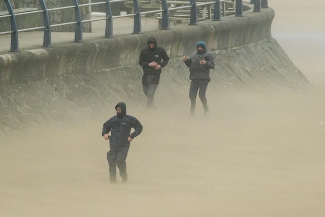 People walk in high winds along the seafront in Newquay on the Cornish coast