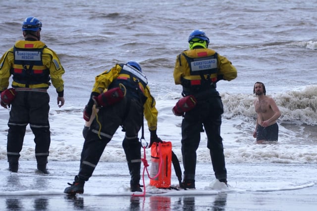A coastguard search and rescue team ask a swimmer to come out of the sea in New Brighton, Merseyside