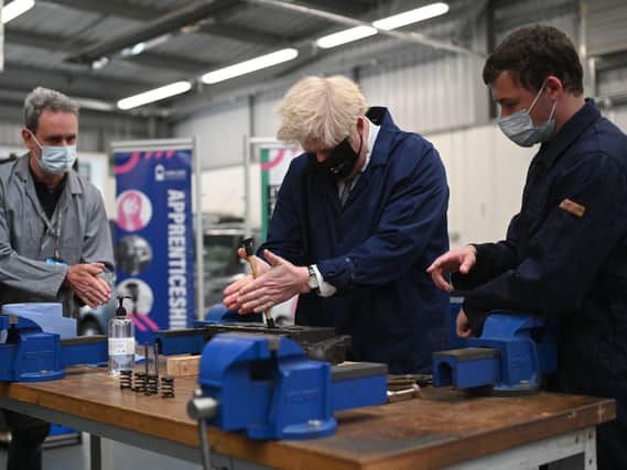 Prime Minister Boris Johnson assists in an engine repair at the automotive shop during a visit to Kirklees College Springfield Sixth Form Centre in Dewsbury. Photo: Getty Images