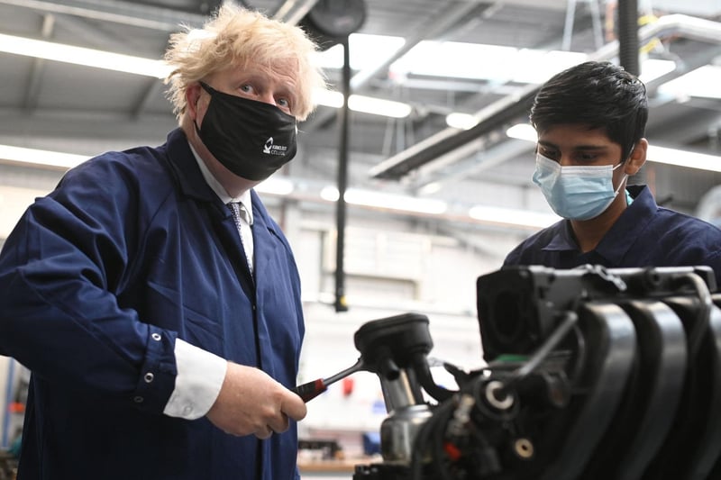 Mr Johnson assists in an engine repair at the automotive shop during a visit to Kirklees College. Photo: Getty Images