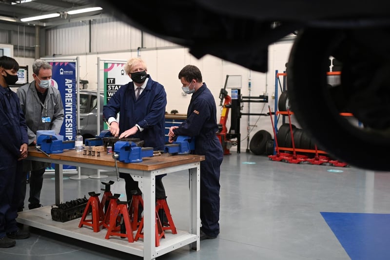 The Prime Minister assists in an engine repair at the automotive shop. Photo: Getty Images