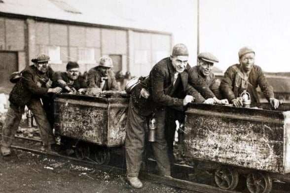 A group of miners who are members of the Castleford Rugby League team, at work on their coal tubs at the mine in Yorkshire. The tubs make excellent practice for scrum work, and the team are famed for their powers in the scrum.