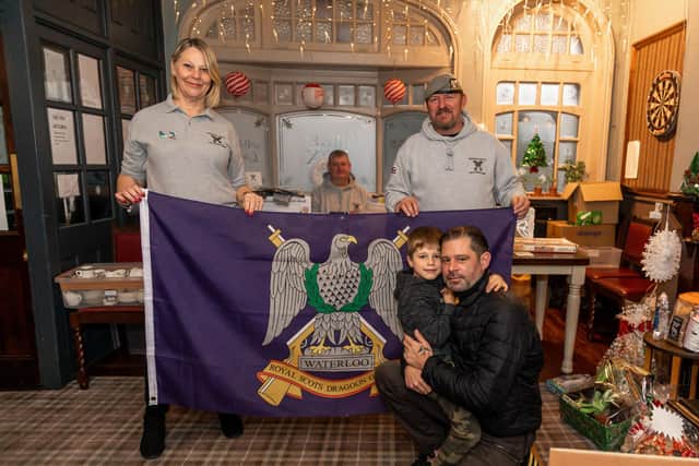 Regimental colours with Paula Hinkley (57), Nigel Kendall (51), founder Kris Darling (43) and Reggie Slapka (7) and dad James Slapka (38). Picture: Mike Cooter (111221)