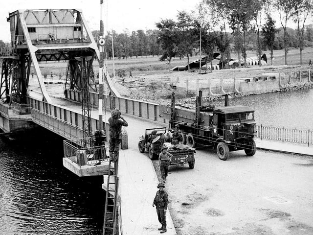 Three days after D-Day and telephone lines are being put up across the soon to be famous Pegasus bridge over the Caen canal.  Airspeed Horsa gliders lay in the fields where they landed at midnight 6/6/1944.  IWM pic B5288