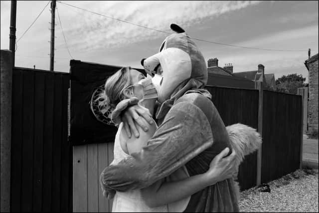 A couple, one of whom is dressed as a squirrel, embrace after playing darts in their garden.

Credit: Bob Aylott
