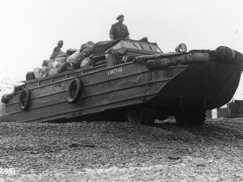 The LCI(L) or Landing Craft, Infantry (Large) landing craft in the background is at a temporary pier alongside South Parade Pier, put up to speed up the loading of troops heading for Normandy, for D-Day and after. The DUKW amphibious vehicle on the beach was probably used by the troops organising the loading process, and helped load some equipment onto the landing craft. Stone blocks just visible behind had been put there earlier in the war in case of enemy landings.