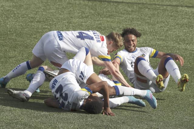 Jake McCarthy is bundled by his team-mates after netting the opener in Hawks' win over Eastbourne Borough Picture: Dave Haines