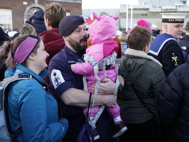Petty Officer Nicholas Baker holds his daughter Amelia-Rose after the Royal Navy aircraft carrier HMS Prince of Wales returns to Portsmouth Naval Base following it's three-month deployment to the Eastern Seaboard of the United States, where the Prince of Wales has been undergoing trials and operating with aircraft and drones. Picture: Andrew Matthews/PA Wire.