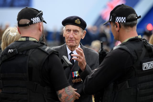 Former British Royal Marine, and D-Day veteran Jim Booth (C), talk with armed members of Britain's police.