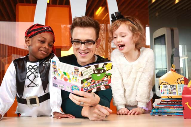 Children's author and musician Tom Fletcher reads to four year olds Zane-Ellis Yeboah (left), and Maisie Patey,  as he is unveiled as the new McDonald's Happy Readers Ambassador to celebrate World Book Day, London.