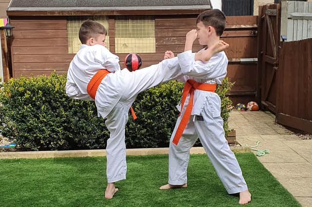 Mark Hague, 10, catches the roundhouse kick of his brother, Myles, nine, before sweeping him  Photo: Pauline Hague