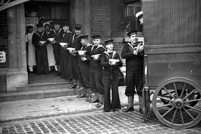 A line of sailors at the Royal Naval barracks at Portsmouth pass Christmas puddings to their comrades from the back of a wagon in December 1933. (Photo by PNA Rota/Getty Images)
