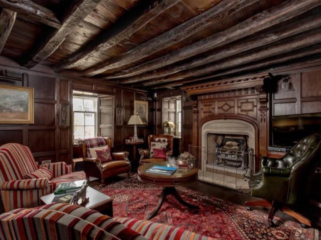 An oak pillared covered passageway leads outside the sitting room, which boasts a raised stone fireplace, flagstone flooring, oak beams and glazed doors all around.