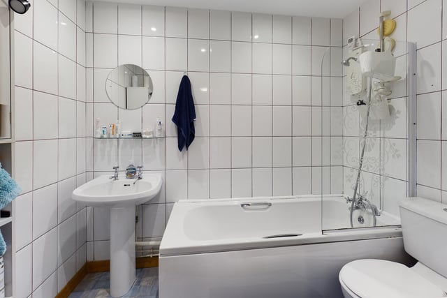 The bathroom is fully tiled with a white suite, a shower over bath and benefits from a towel rail.