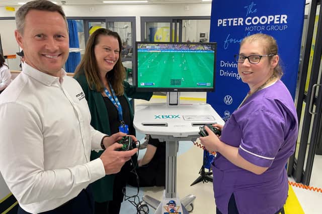 Darren Cooper, Managing Director at The Peter Cooper Motor Group and Zoe Parton, Play Specialist for the Children’s Emergency Department try out the new Xbox