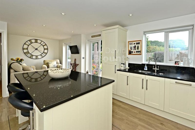 Another view of the modern and impressive breakfast-kitchen. It includes an island unit, an inset one-and-a-half stainless steel sink unit and granite worktops.