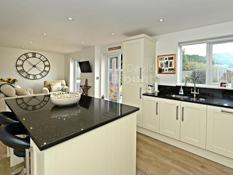 Another view of the modern and impressive breakfast-kitchen. It includes an island unit, an inset one-and-a-half stainless steel sink unit and granite worktops.