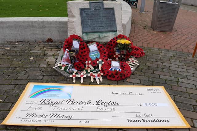 Team Scrubbers have raised £5,000 for the Royal British Legion through selling poppy face masks. Pictured: The commemorative cheque at the memorial in Gosport